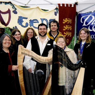 eight people standing behind two harps in a highland games harp tent