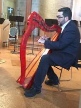 Man playing small red harp and singing